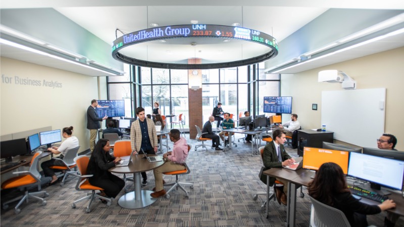 RIT students in the Saunders College of Business sitting under a stock ticker