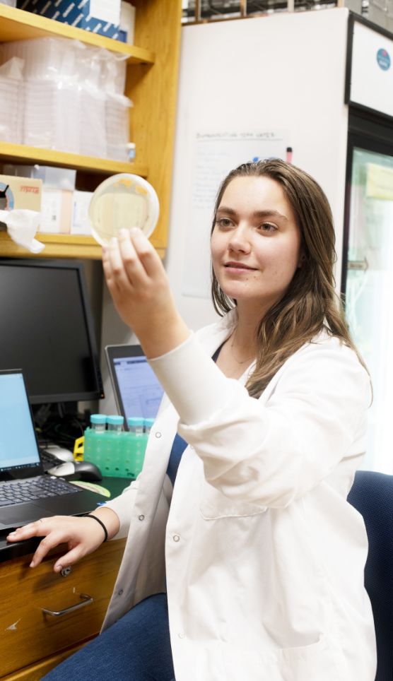 girl in a whitecoat holding up a peetree dish