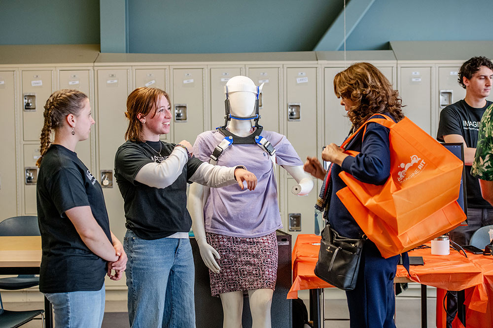 Two female students discuss a neck brace on a mannequin.