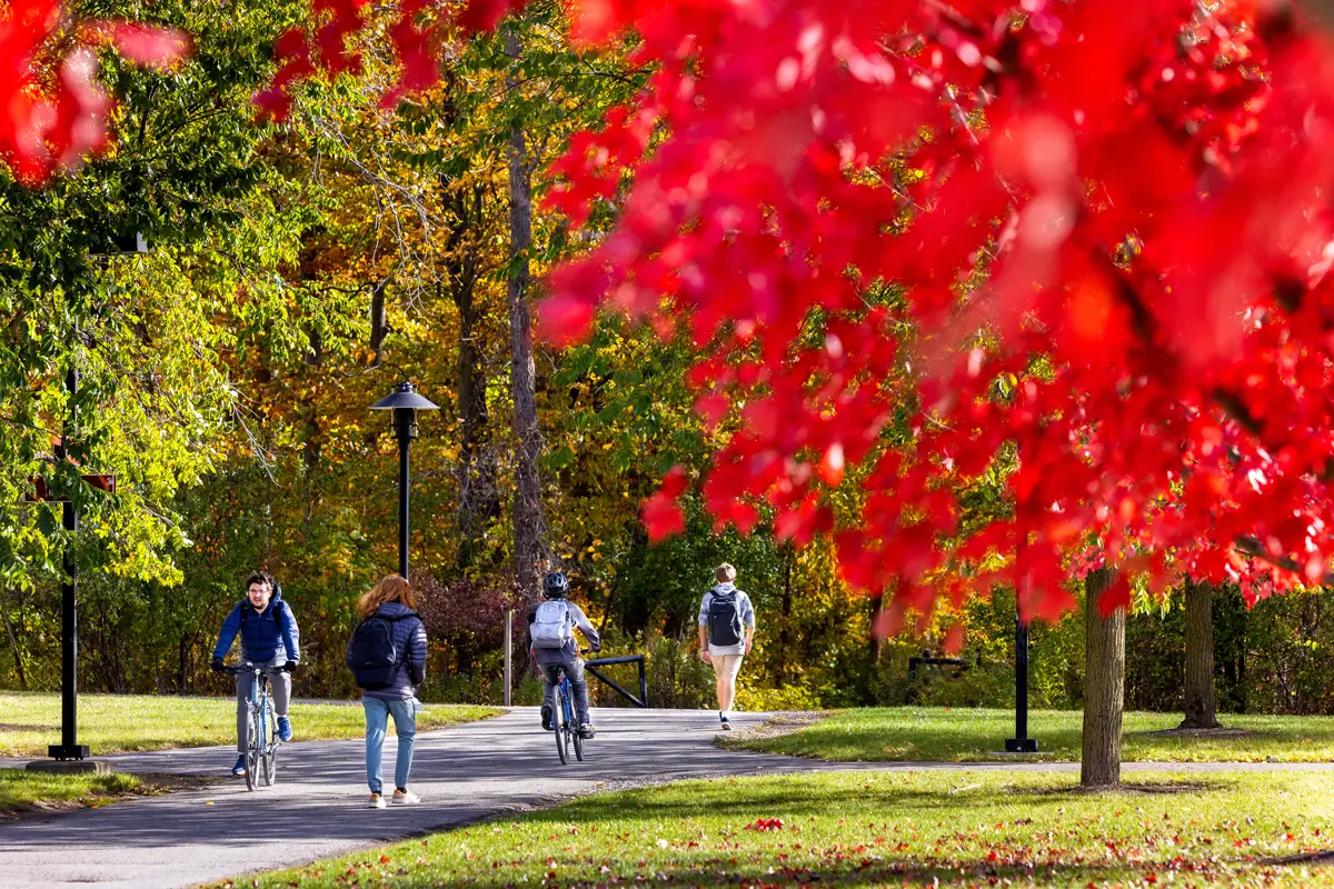 Students walking and riding bike on a sunny Fall day on the R I T campus.