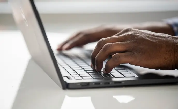 Close up of hands on a laptop keyboard.