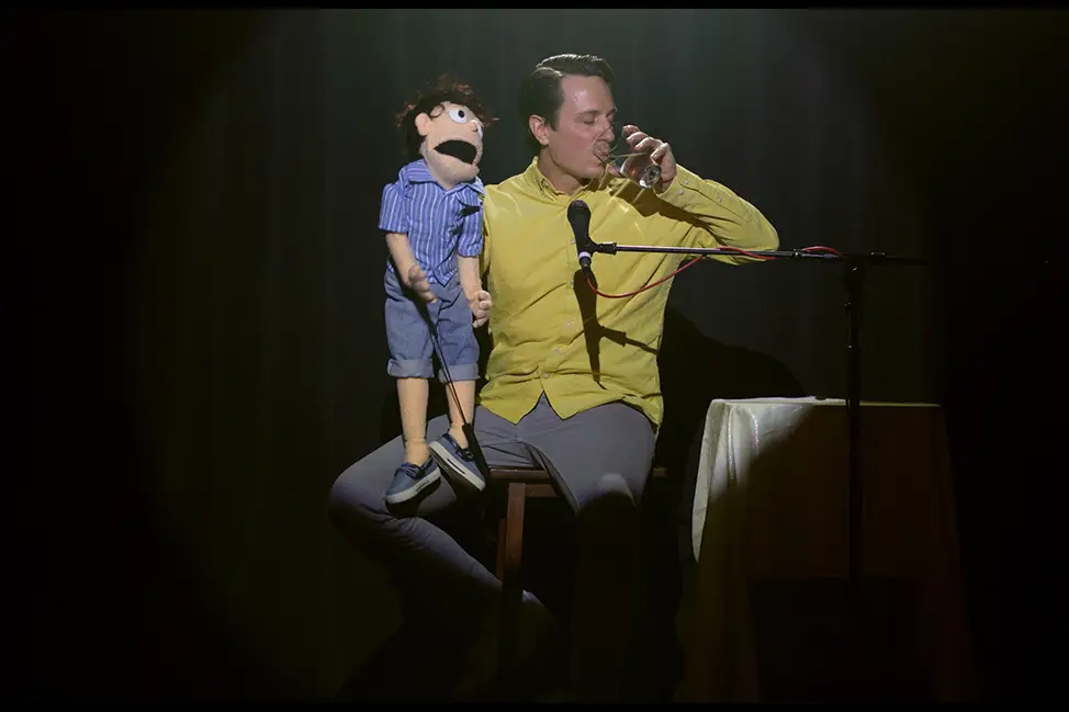 Man sitting on a stool with a puppet on his lap
