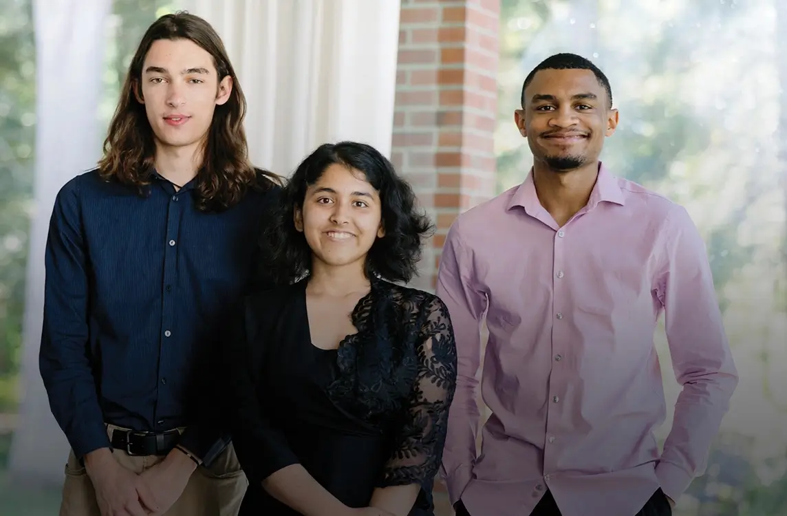 Three R I T students smiling while looking into the camera.