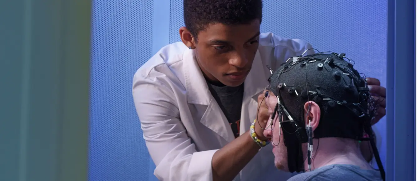 A research assistant fitting a volunteer with a cap with sensors on it.
