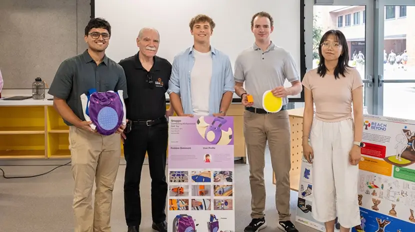 Five people posing for a photo behind a poster