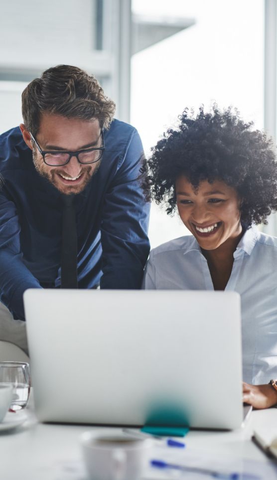 Two people looking at and smiling at a laptop
