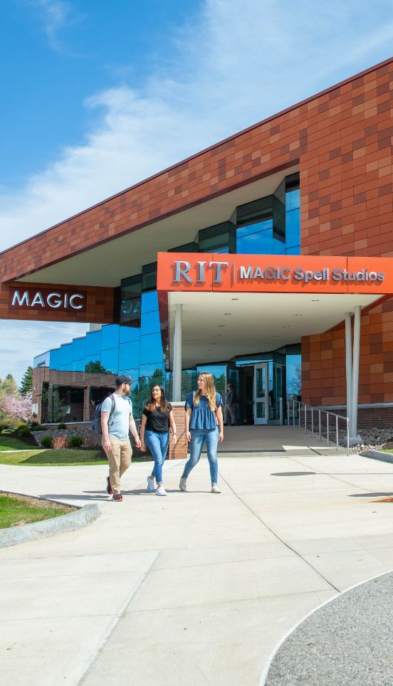 Two students walking on the sidewalk outside a building entrance