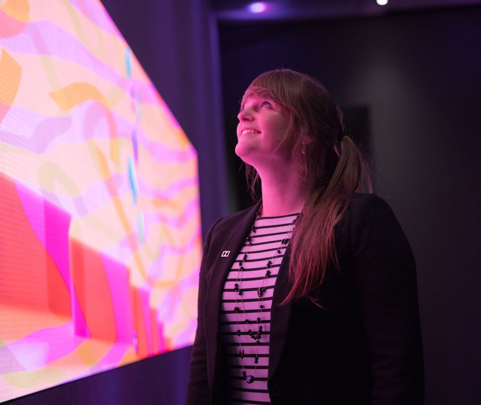 Jaclyn Pytlarz looks at a colorful, vibrant screen.