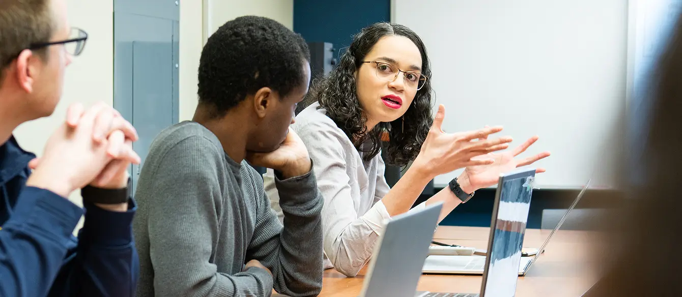 Three people sitting at a desk having a discussion.