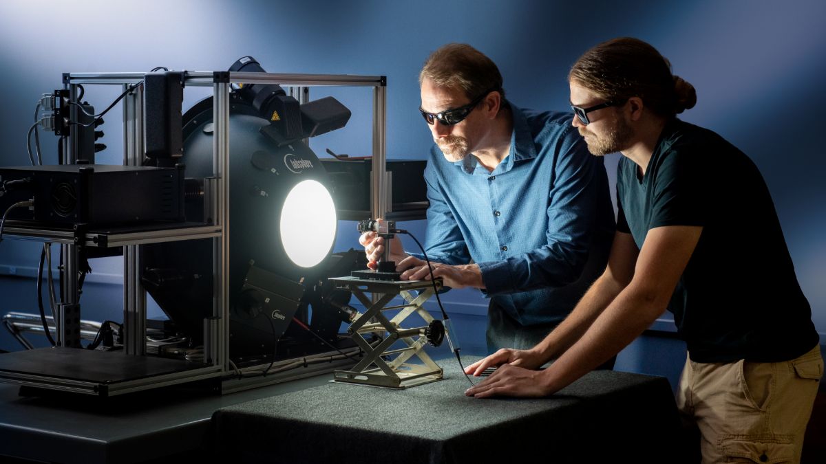 Two people calibrating an imaging device in a low-light room.