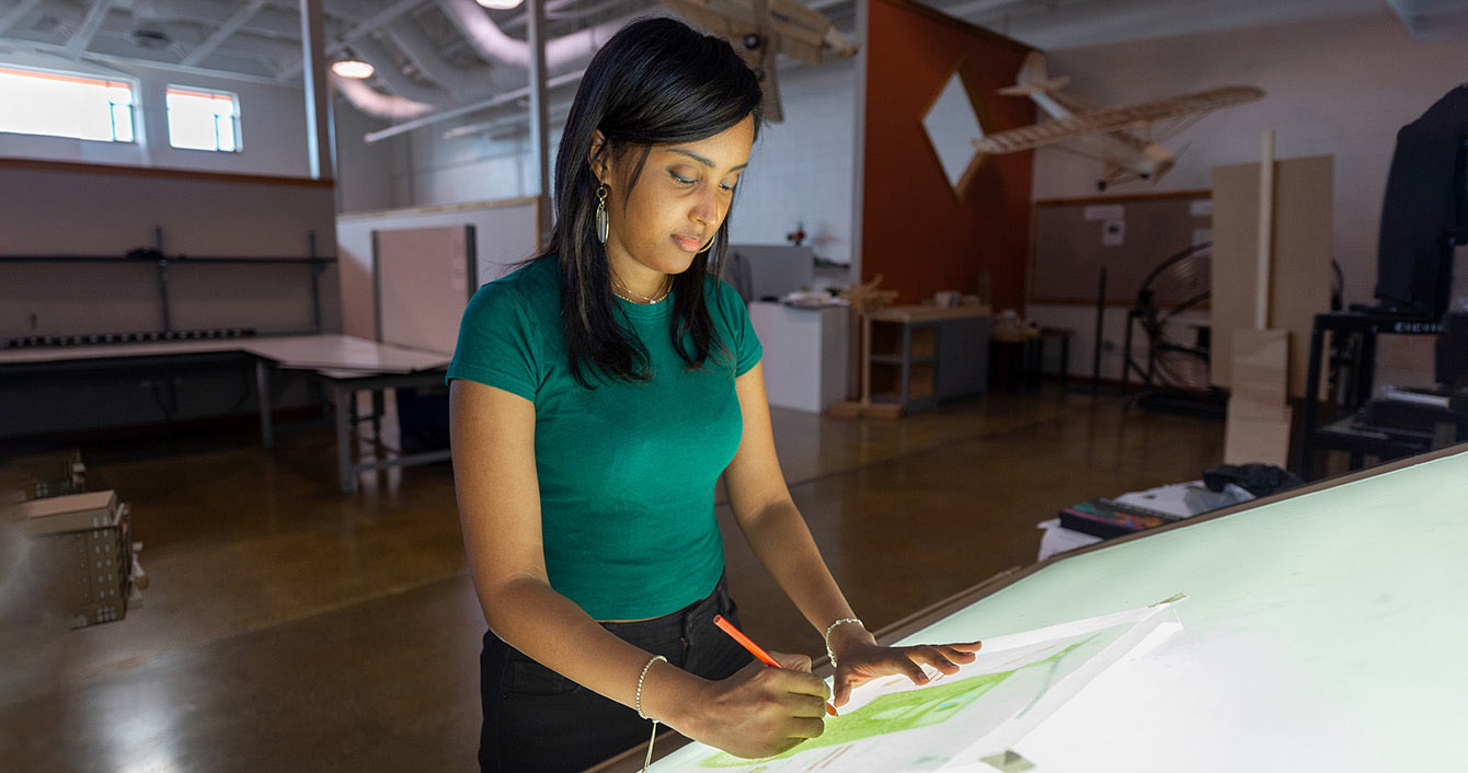 A woman wearing green works at a light board.