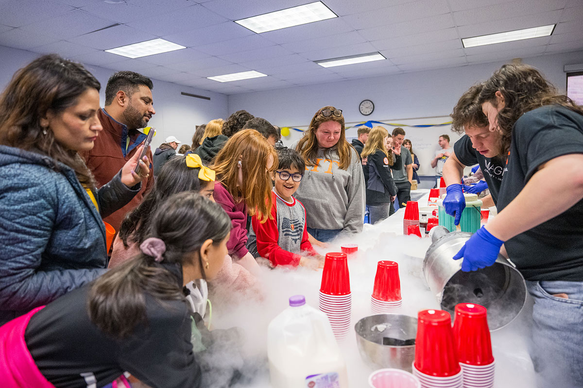 Visitors watch as students use liquid nitrogen to create ice cream.
