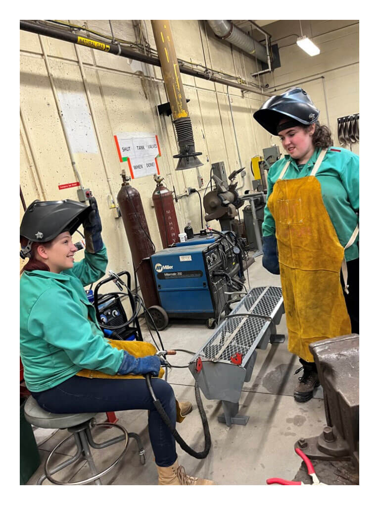 Two R I T students crafting a bench for the bus stop.