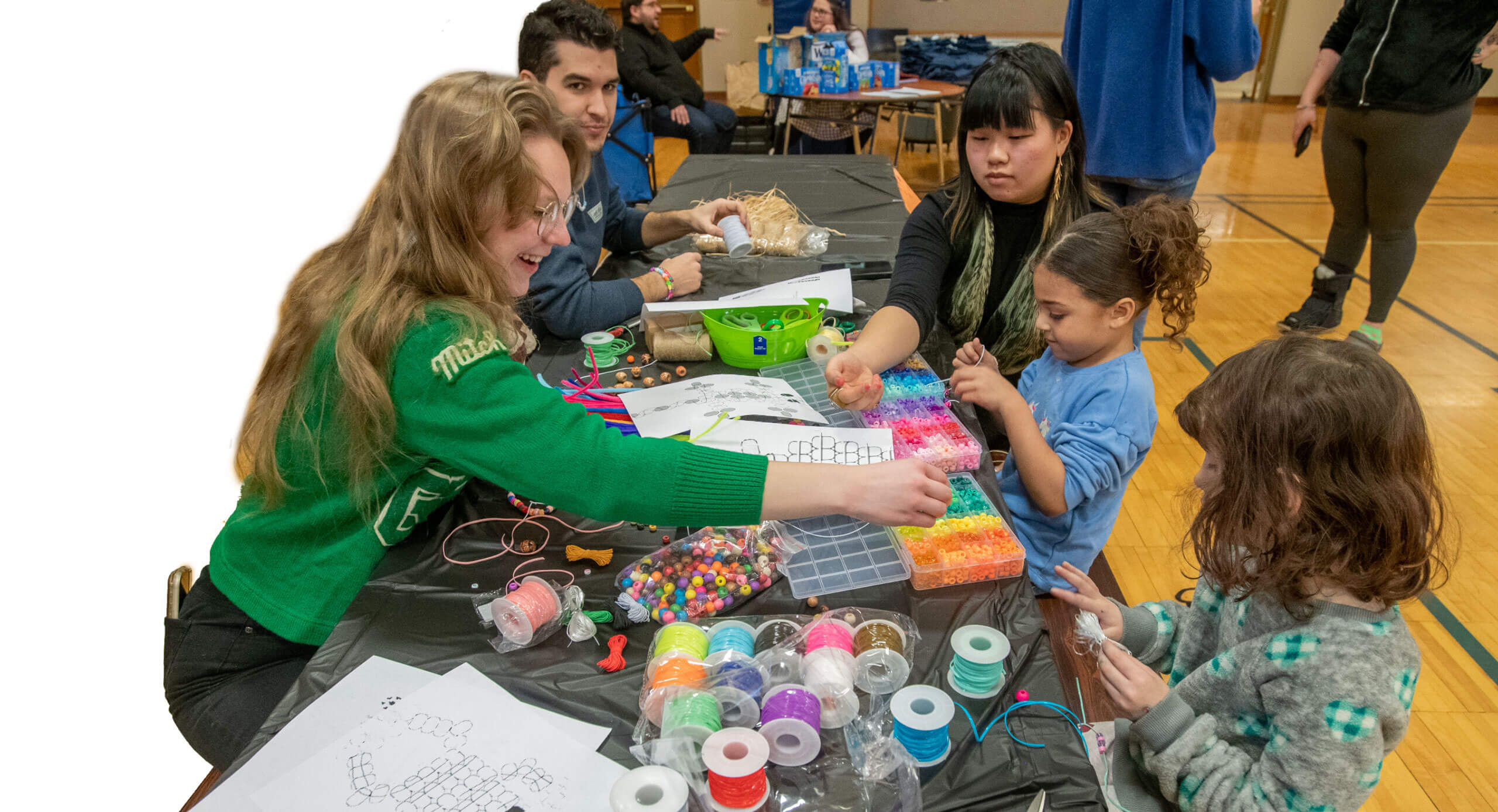 R I T graduate students helping kids create art projects with beads.