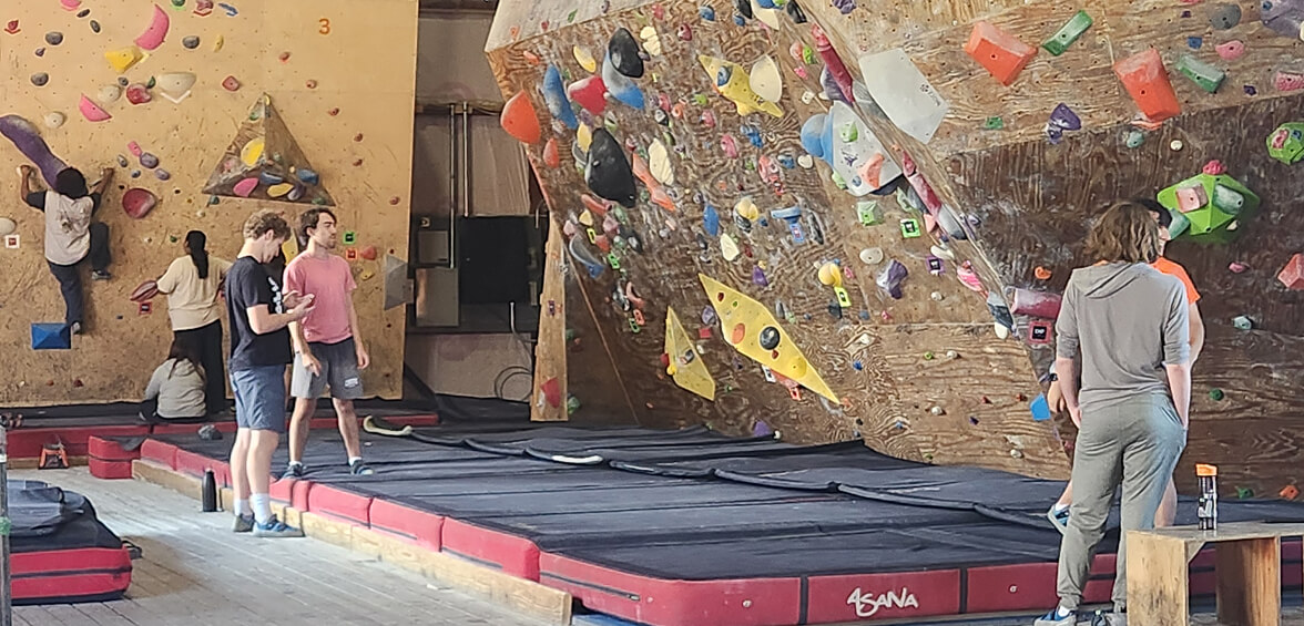 Interior of the Red Barn, R I T's rock climbing gym, showing students climbing and preparing to climb.