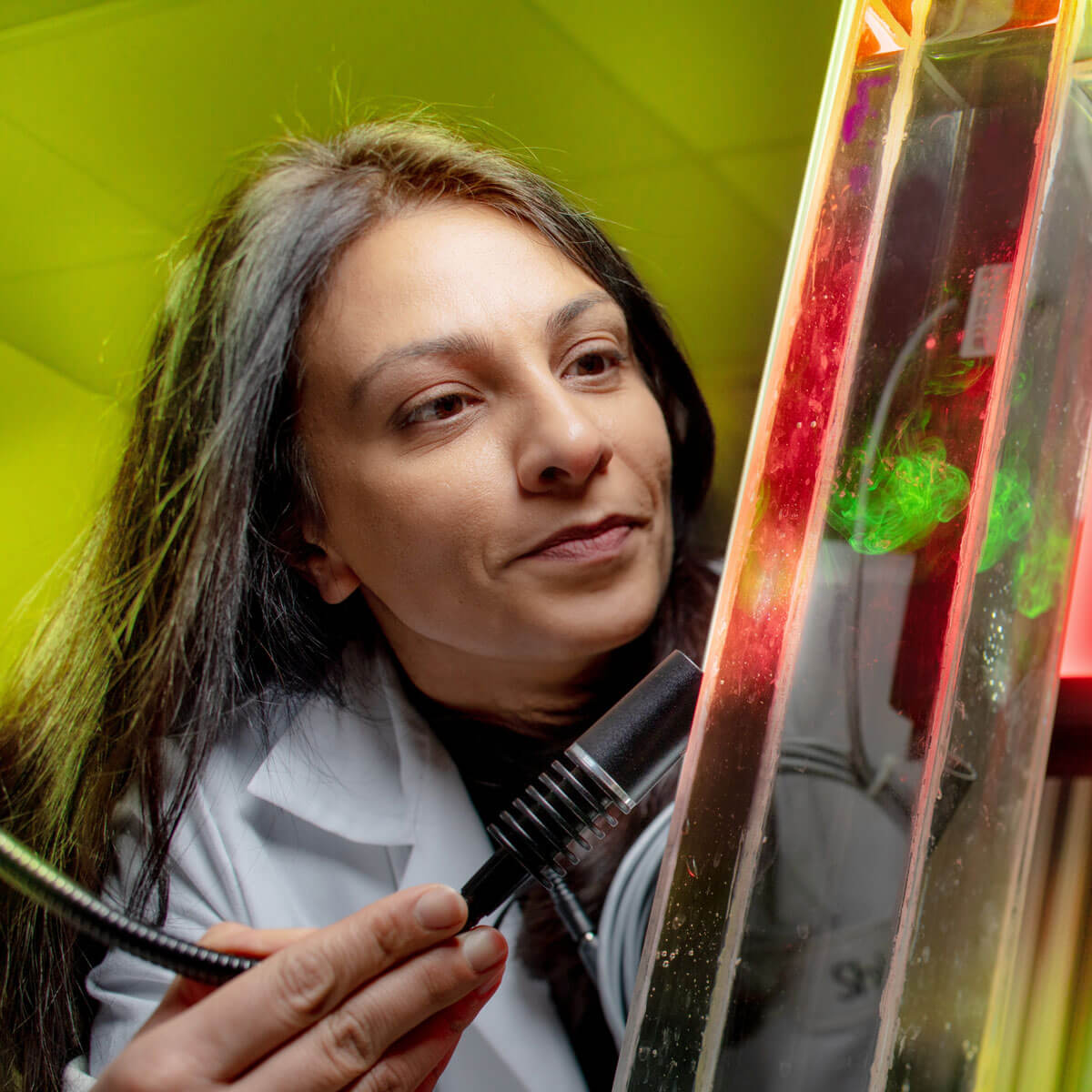 Shima Parsa observing a florescent liquid interacting with different liquid.