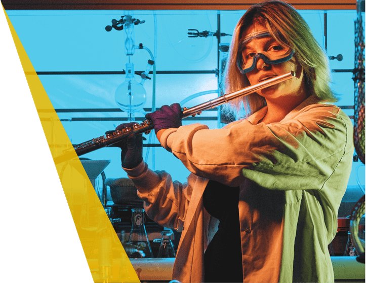 Emily Ruddel playing the flute while wearing a white lab coat and goggles.