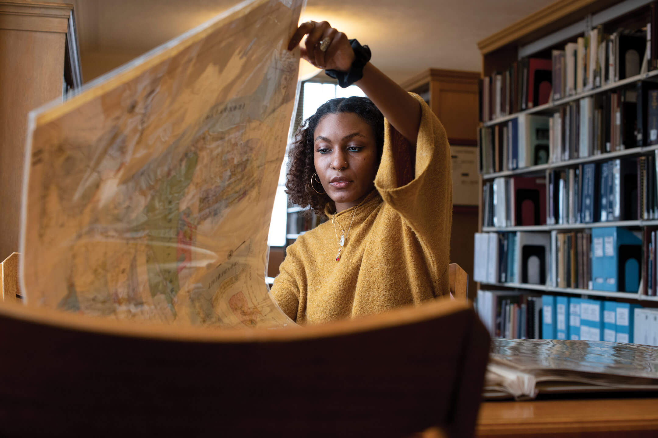 Leah Green looking at a map while sitting in a library.
