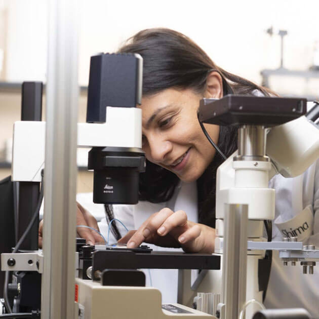Assistant Professor Shima Parsa looking at a sample through a microscope.