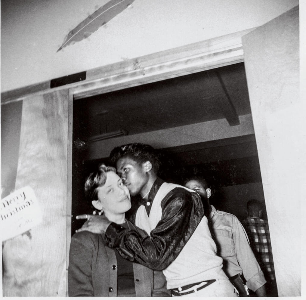 A Black teenage man kissing a white teenage woman in 1956.