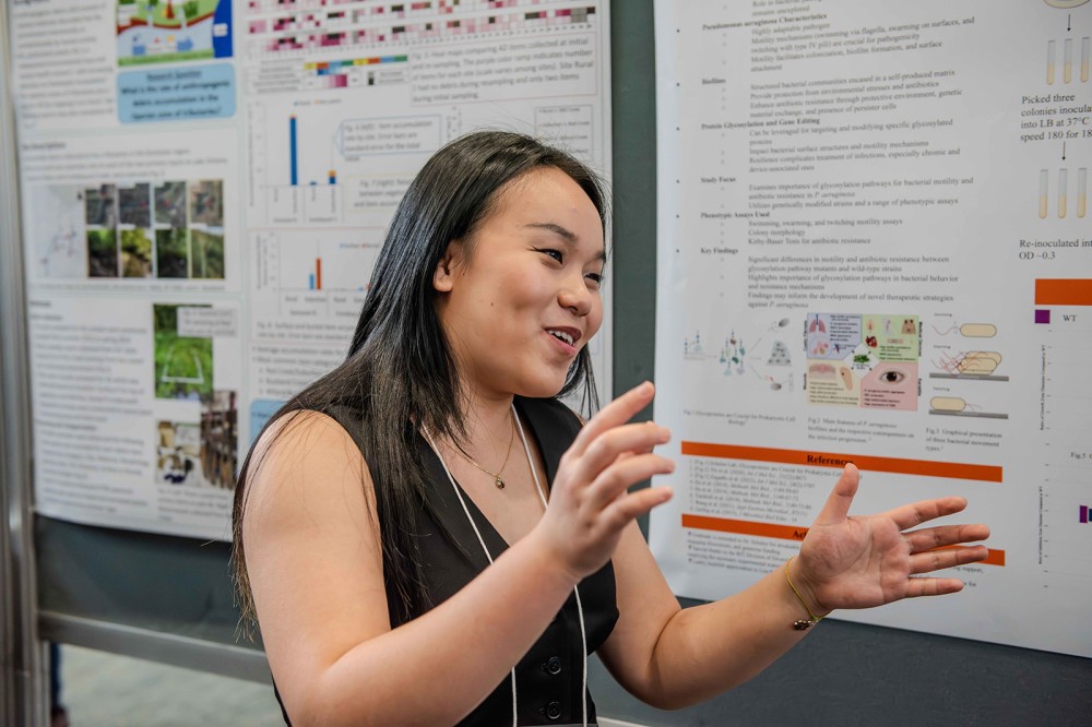 a woman stands in front of a presentation appearing to be speaking to people.
