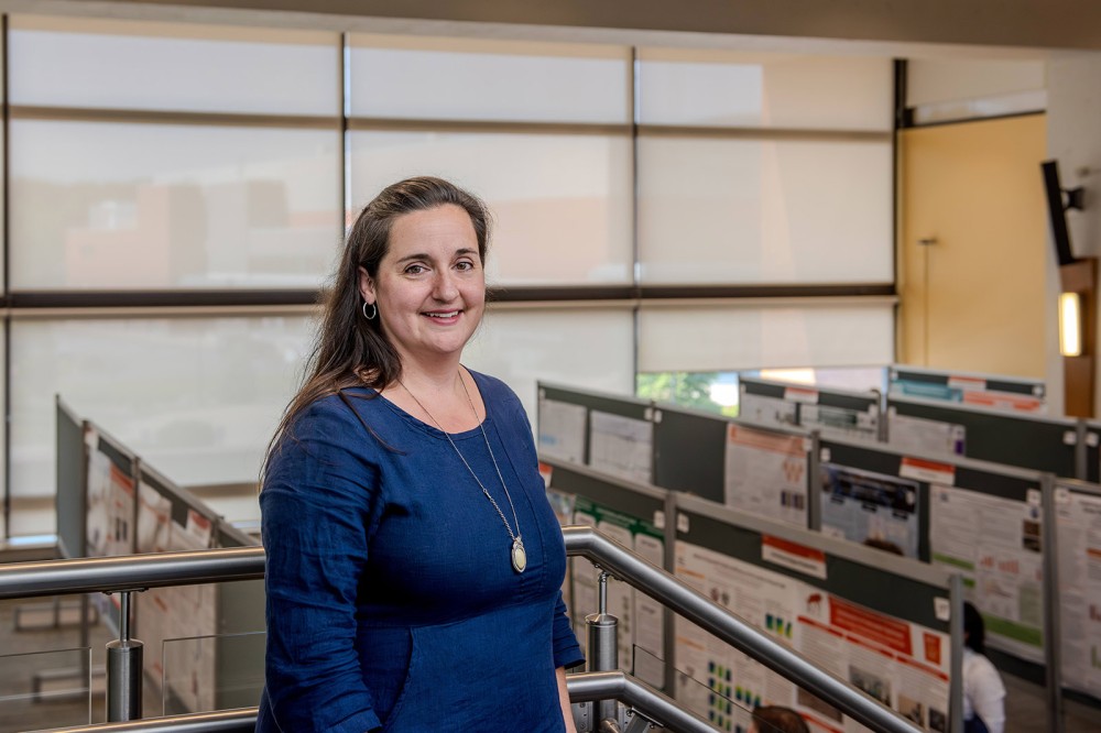 a woman stands on a staircase overlooking the undergraduate research symposium.