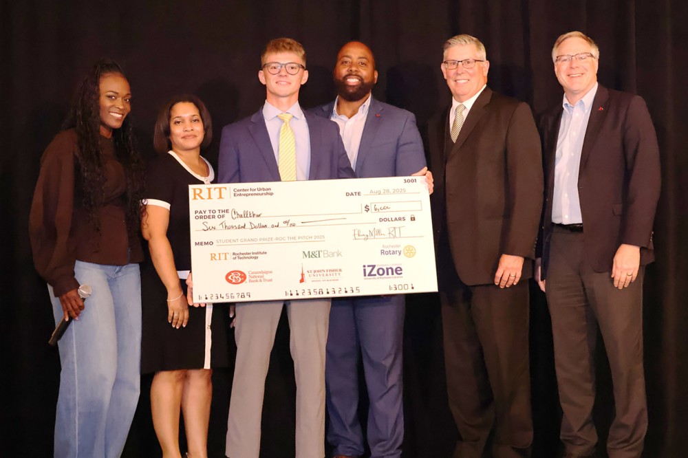 six people stand on a stage holding a comically large check.
