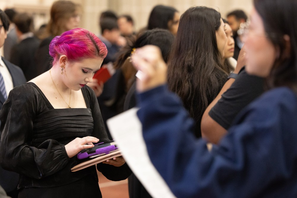 a girl with pink hair consults a list she holds in her hand.