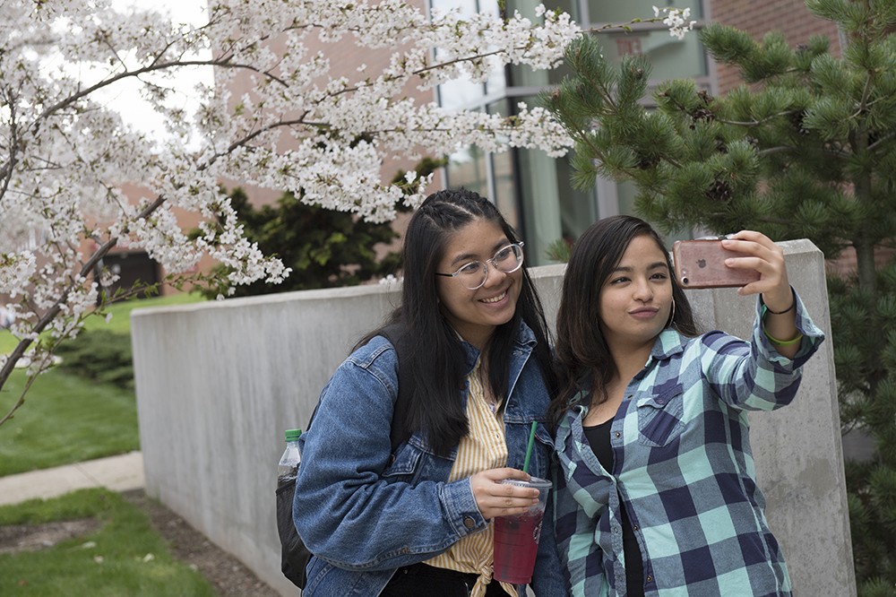 <p>Emely Pacheco, right, a first-year business management major from Delaware, takes a selfie showing a flowering spring tree at NTID with Andrea Miranda, a first-year 3D graphic technology student from California.</p>

