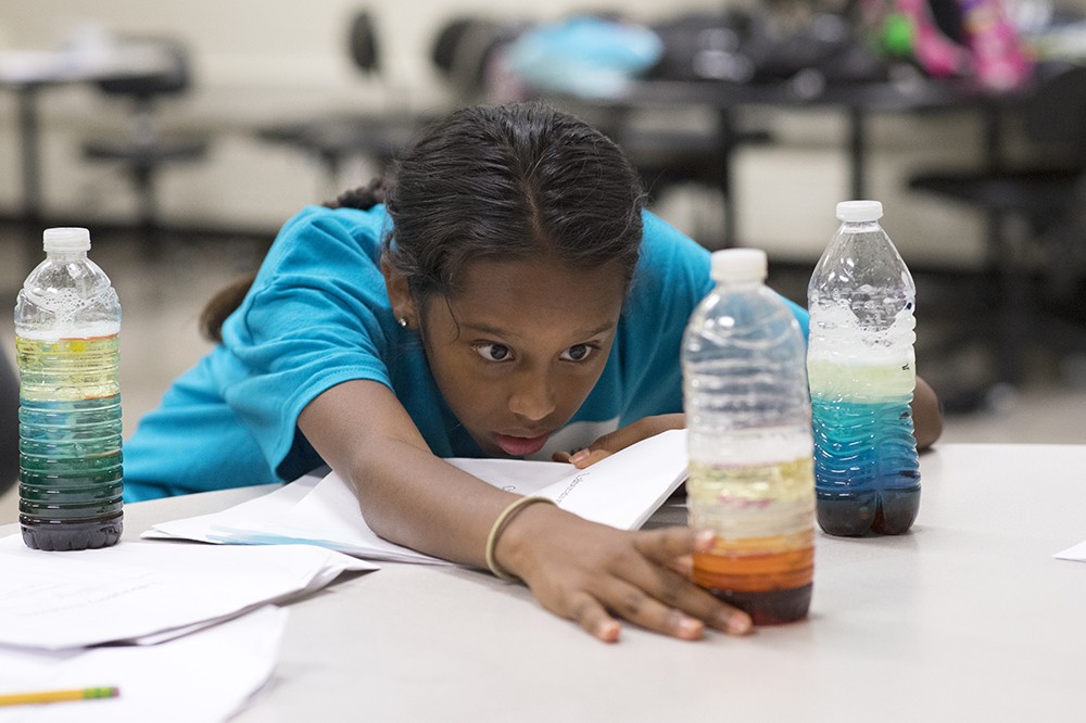<p>Salida Cintron, 12, a Calkins Road Middle School student, examines her bottle that demonstrates different weights of liquids. The experiment was part of a RIT Camp Tiger workshop "Experiments in Science!" for fifth- through seventh-grade students. Camp Tiger, formerly known as Kids on Campus, is a summer day-camp at RIT running from July 8 through Aug. 2.</p>
