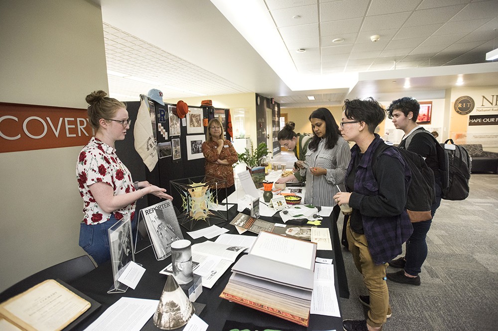 <p>Lizzy Carr, a fourth-year museum studies student from Northport, NY, describes some of the items from the RIT Archives to students. The event,&nbsp;part of New Student Orientation, showcased interesting artifacts and treasures from RIT's past.</p>
