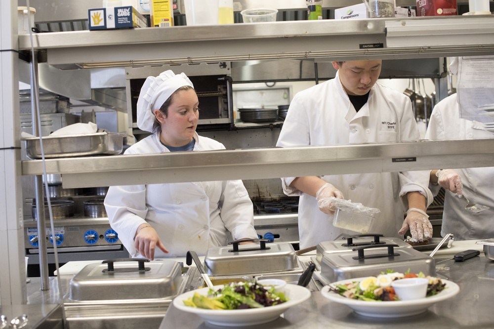 two students preparing food in kitchen