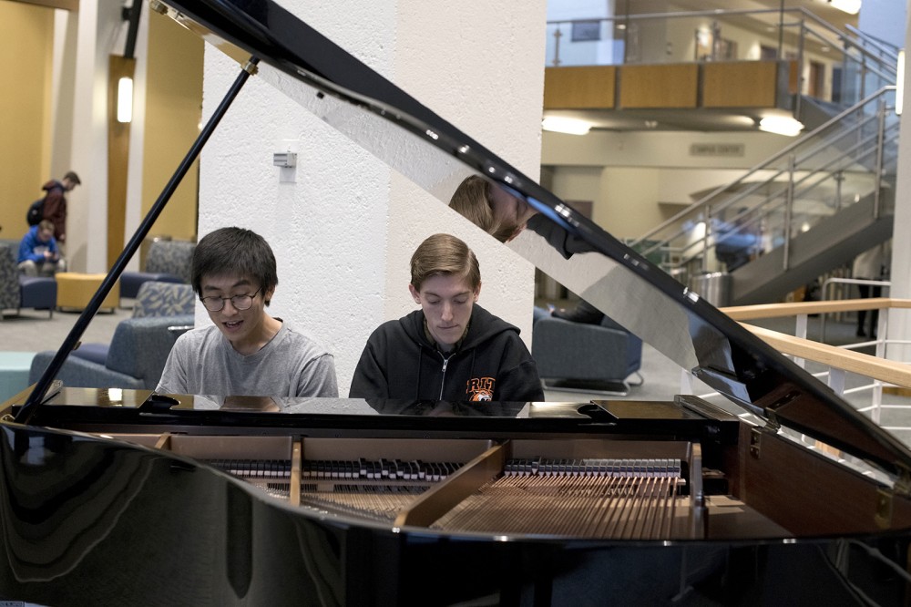 two male students playing piano