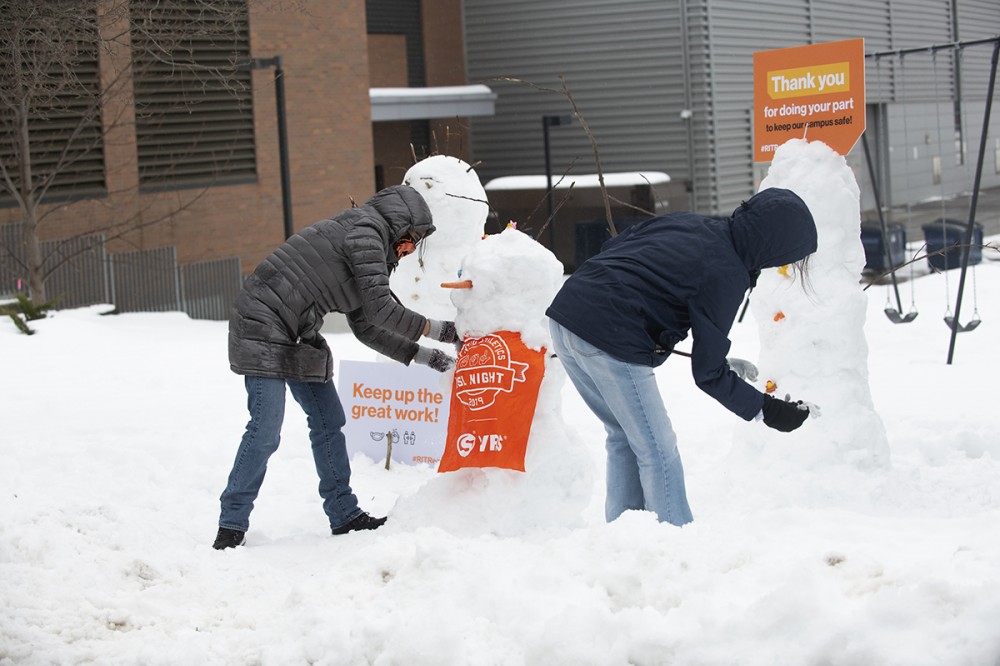 two students buiding a snow person.