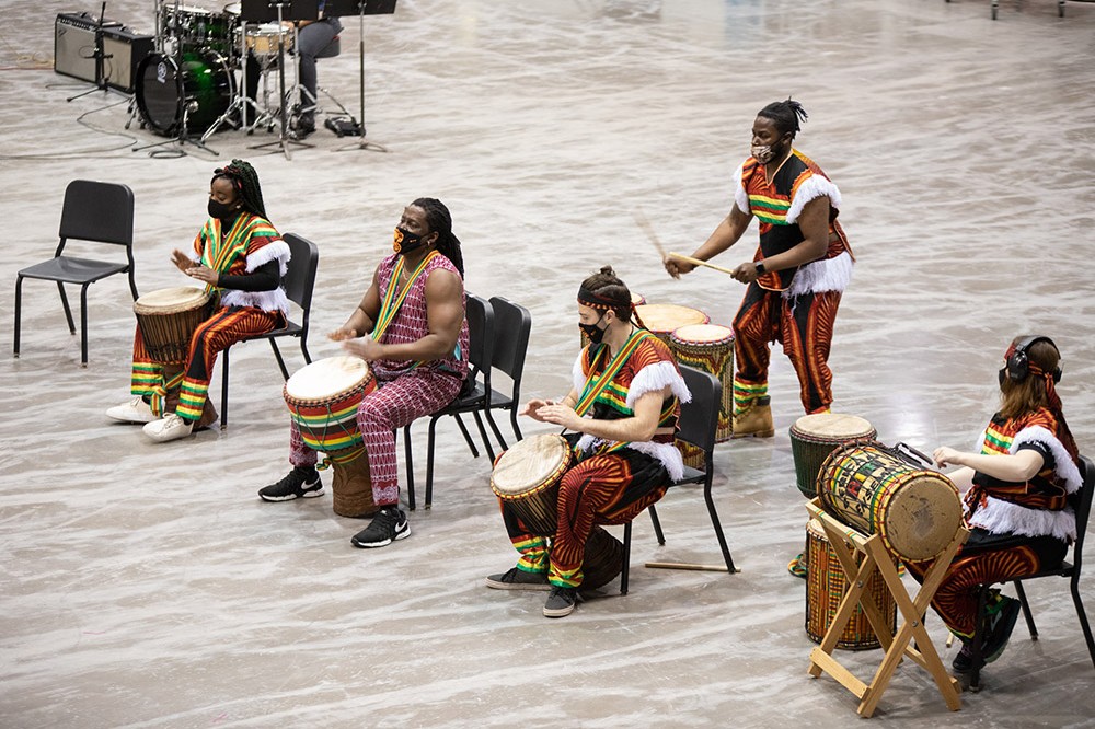 students wearing tradiational African clothing playing drums.