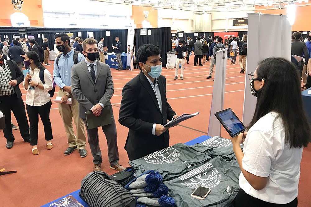 students line up to speak with company representative at a career fair.