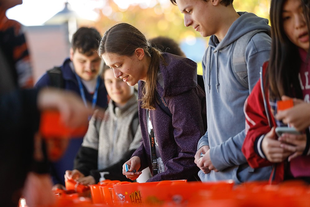 line of students picking candy out of buckets along a table.