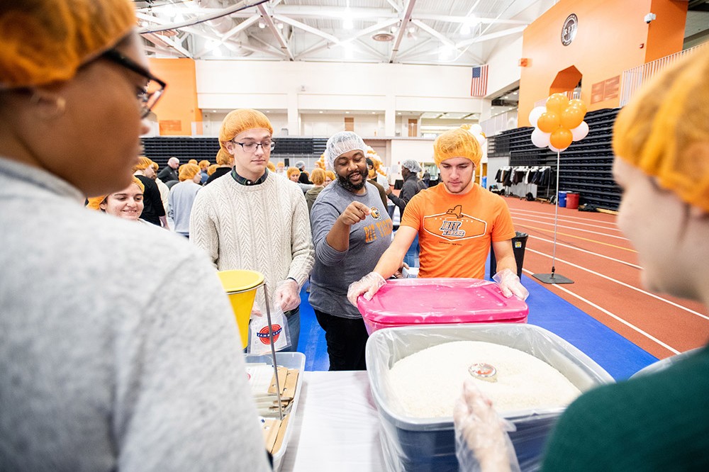 volunteers in an assembly line to fill bags with dry ingredients.