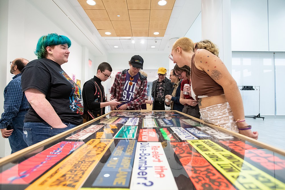 museum visitors looking at a display of bumper stickers.