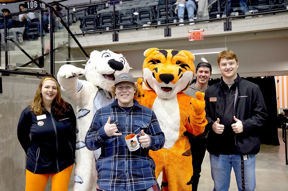 two tiger mascots posing with four college students.