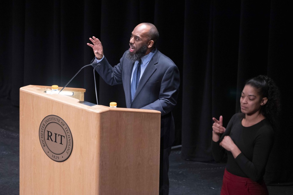 Professor speaks at podium next to sign language interpreter