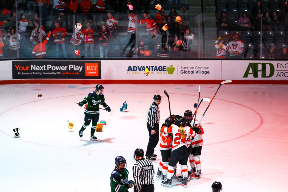female hockey players skate around the ice as stuffed animals are thrown on to the ice