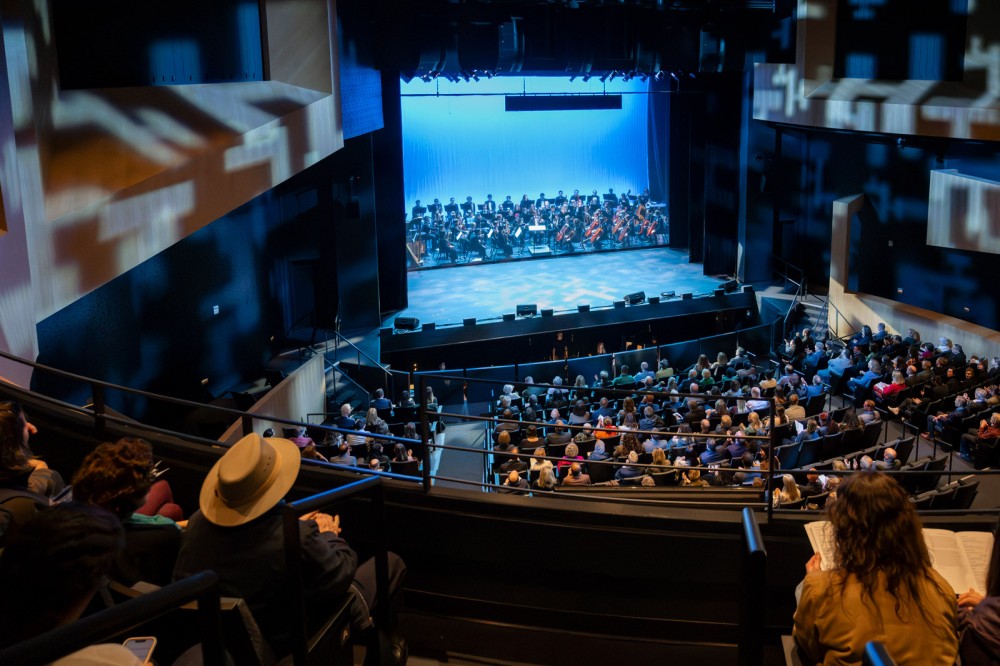 Audience watches orchestra on modern theater stage