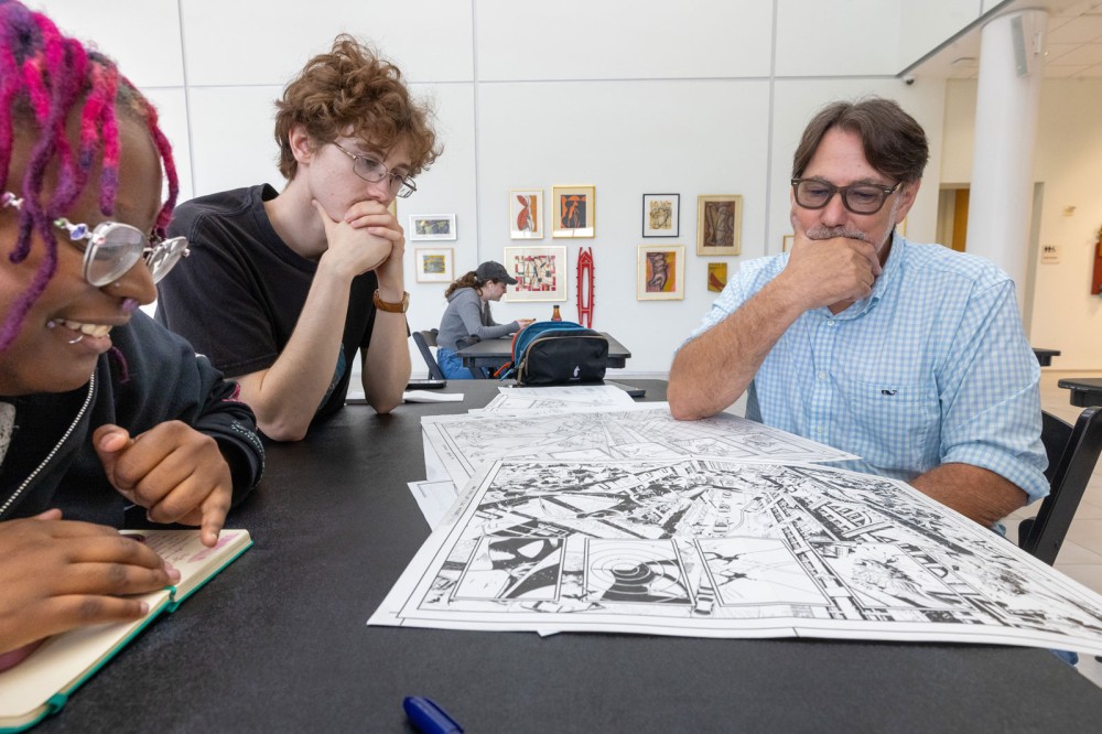 RIT students Valentine Johnson and Ben Otto look through work by Marvel comics artist Adam Kubert 