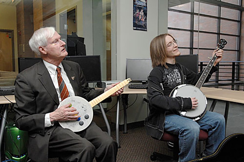 President Destler and student play banjos.