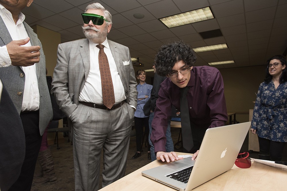 RIT Trustee Ronald Zarrella, left, prepares to view an interactive game developed by Rochester Prep students Terrell Marble and Zaid Abdulsalam, on right. This fall, seven seniors from Rochester Prep High School met with RIT faculty to work on capstone projects varying from photojournalism to microbiology to game design and development. The students presented the final results of their projects at a special capstone showcase ceremony March 21.