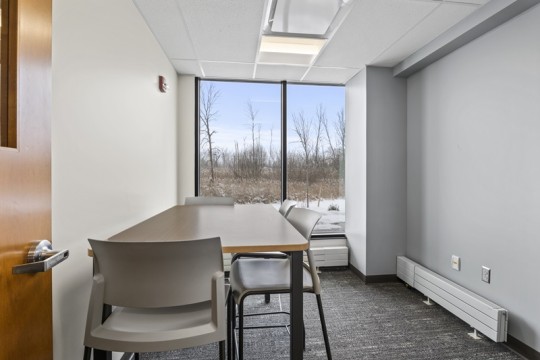 a small meeting room with a table and four chairs.