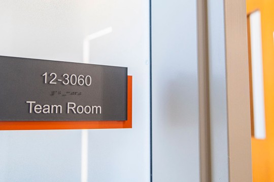 a sign on a glass wall that reads, 12 dash 30 60, team room