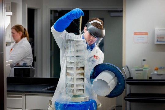 A student pulling equipment out of a liquid nitrogen container.