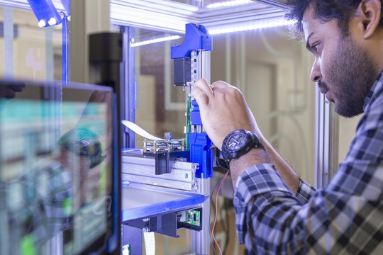 A close up of a student working with a machine in the AMPrint Center.